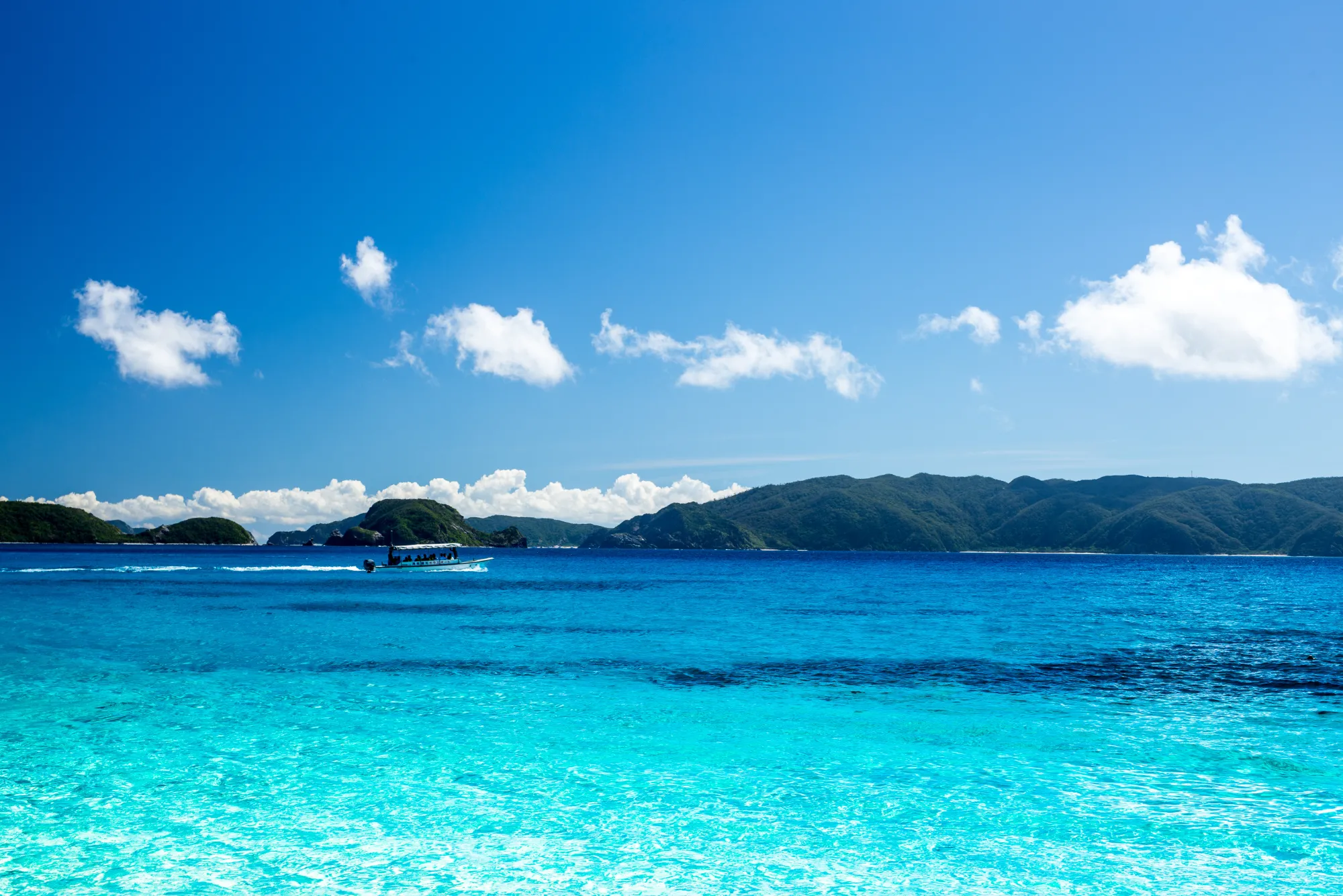 青い海を走る船と島影